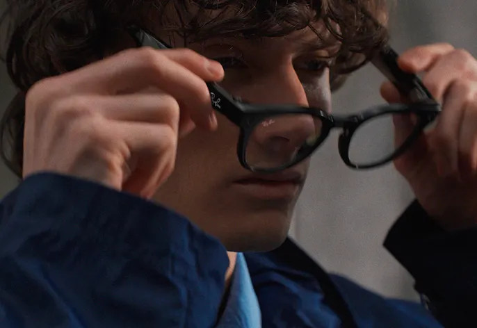 Joven ajusta unas gafas inteligentes Ray-Ban Meta negras antes de capturar contenido con manos libres.