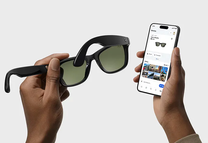 Manos sostienen gafas de sol Ray-Ban Meta y móvil con la app Meta AI abierta.