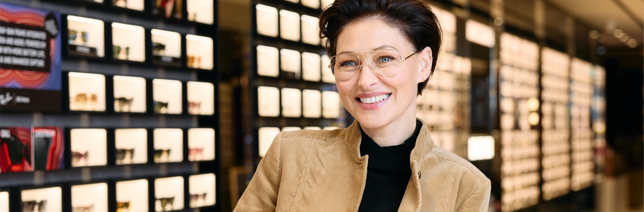 A woman with short dark hair wears a pairs of glasses on a Vision Express store.